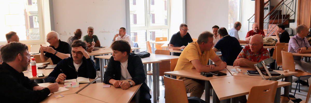 Participants at work around tables during a session in Rome.