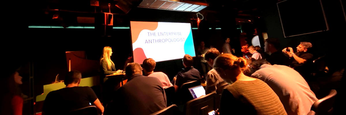 An audience watching a talk in a darkened venue in Stockholm.